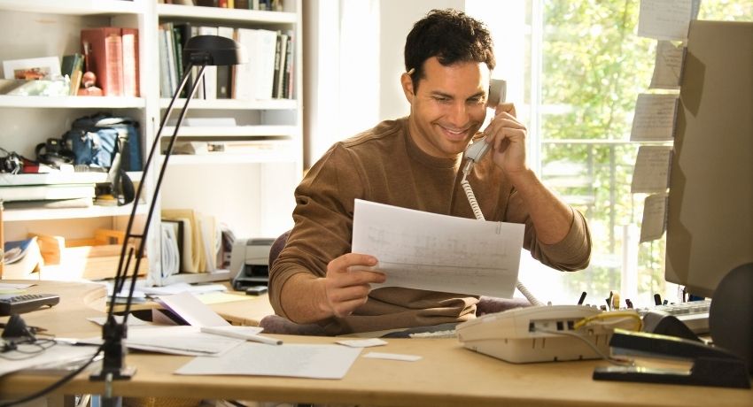 colaborador falando ao telefone e trabalhando em casa - brindes para o home office