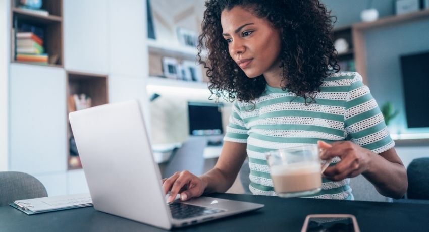 funcionário trabalhando em seu computador com uma xícara de café - brindes para o home office