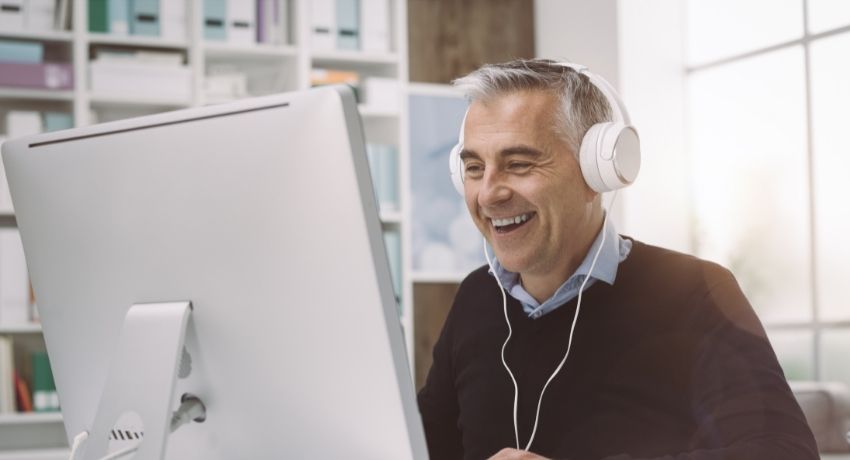 Colaborador feliz assistindo live no computador - fim de ano no home office